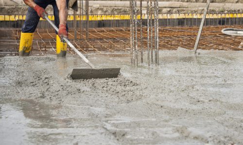 bricklayer at work on a construction site during the laying of concrete to build the foundations of a house