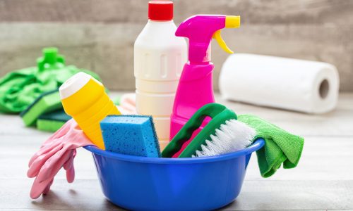 Cleaning products on the floor, home interior background. Chemical detergent bottles in a blue bowl. Domestic household or business sanitary cleaning