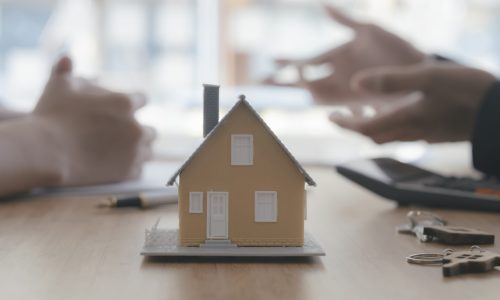 Close up house model on blur background of real estate agent and customer. Business and finance of buy sell and rent real estate concept.