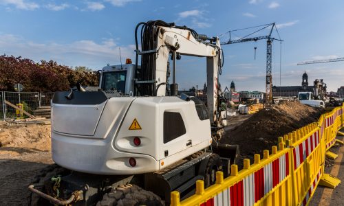 Construction site on the street of the old european city. Excavator on sand pile in downtown, building engineering