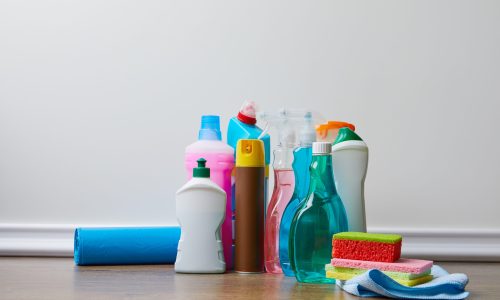 different bottles with domestic supplies for spring cleaning on wooden floor