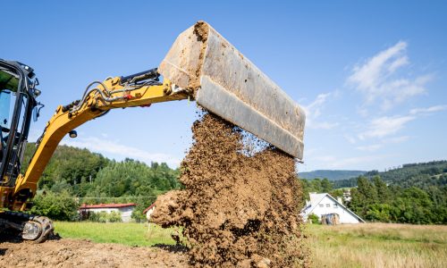 Mini excavator digging preparing ground under home garden