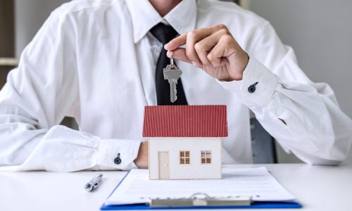 Real estate agent Sales manager holding filing keys to customer after signing rental lease contract of sale purchase agreement, concerning mortgage loan offer for and house insurance.