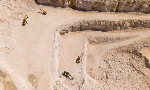 the flight of the drone over a quarry of sand and white stone, in the image you can see excavators that are stopped. aerial view of the stone and sand industry